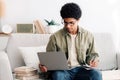 Remote learning concept. Industrious black teen student with laptop computer taking notes during online lecture at home Royalty Free Stock Photo