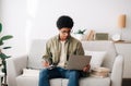 Remote learning concept. Industrious black teen student with laptop computer taking notes during online lecture at home Royalty Free Stock Photo