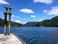 A remote photo of a wooden dock spcae for a boat surrounded by beautiful ocean and forested mountains in saanich inlet, Vancouver