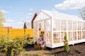 Remote view of elegance blonde young mother in dress sitting on doorstep of summer gazebo house with two little adorable Royalty Free Stock Photo