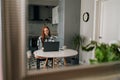 Remote view of happy freelancer female working typing on laptop computer sitting at table smiling looking to screen in Royalty Free Stock Photo