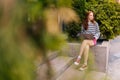 Remote view of pensive hipster female tourist working with laptop sitting on steps, outdoor. Young woman student in Royalty Free Stock Photo