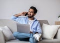 Remote Work. Arab Man Using Laptop And Talking On Cellphone At Home Royalty Free Stock Photo