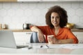 Remote Work. Black Woman Drinking Coffee While Working With Laptop In Kitchen Royalty Free Stock Photo