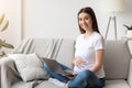 Remote Work Concept. Beautiful young pregnant woman with laptop sitting on sofa Royalty Free Stock Photo