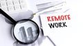 Remote work concept displayed with magnifying glass, charts, and office tools Royalty Free Stock Photo