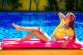 Remote work dream job.young woman sitting on inflatable pink mattress in the swimming pool having sunbath and working on Royalty Free Stock Photo