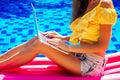 Remote work dream job.young woman sitting on inflatable pink mattress in the swimming pool having sunbath and working on Royalty Free Stock Photo