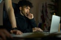Remote work. Focused young guy with piercing sitting in front of laptop screen while working late in the evening Royalty Free Stock Photo