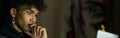 Remote work. Focused young guy with piercing sitting in front of laptop screen while working late in the evening Royalty Free Stock Photo