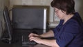 Remote work. A middle-aged woman wearing glasses is sitting at the computer Royalty Free Stock Photo