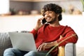 Remote Work. Smiling Indian Freelancer Guy Using Laptop And Cellphone At Home Royalty Free Stock Photo