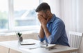 Remote Work Stress. Tired freelancer man sitting at desk at home office Royalty Free Stock Photo