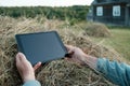 Remote work with a tablet on a haystack, against the background of a rustic wooden house and a beautiful landscape Royalty Free Stock Photo