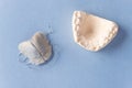 Removable orthodontic plate and plaster cast of child`s jaw on blue background.