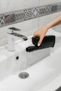 Removal of blockage in the sink, the hand of a woman with a bottle of a special remedy with liquid remedy.