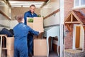 Removal Company Workers Unloading Furniture And Boxes From Truck Into New Home On Moving Day Royalty Free Stock Photo