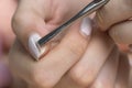 Remove the gel polish with a metal pusher. Woman is removing gel polish shellac from nails using pusher, manicure at home.