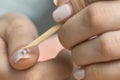 Remove the gel polish with a wooden stick. Woman is removing gel polish shellac from nails using pusher, manicure at home.