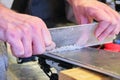 Removing excess wax from ski base using a plexi scraper - focus on the wax. Preparing the base of a ski before brushing.