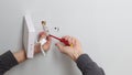 Removing faulty ceiling LED panel, an electrician disconnects power supply wires from house wiring terminal block.