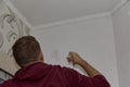 Removing off old wallpaper from the wall with a spatula. Preparing for renovation of the room. Royalty Free Stock Photo
