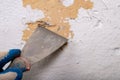 Removing old paint from the wall with a metal spatula. Small painting works at home