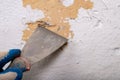 Removing old paint from the wall with a metal spatula. Small painting works at home Royalty Free Stock Photo