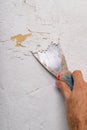 Removing old paint from the wall with a metal spatula. Small painting works at home Royalty Free Stock Photo