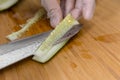 Removing the seed pit and core of a cucumber with a sharp stainless knife while wearing plastic gloves