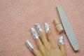 Removing shellac. fingers with foil, nail file and nail polish on pink towel