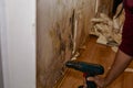 Removing the skirting board by drill before removing old wallpaper, cleaning and painting wall. Preparing for renovation Royalty Free Stock Photo