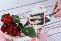 Removing a slice of chocolate cake covered with Swiss meringue buttercream. Three red flowers on top