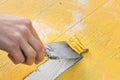 Removing yellow paint with a spatula. Cleaning a wooden surface from paint. Royalty Free Stock Photo