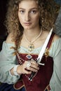 A Renaissance woman wearing a red brocade corset and blue silk skirt and holding a dagger Royalty Free Stock Photo