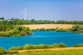 Renewable energy concept. Wind turbine close to river curve in rural area Royalty Free Stock Photo