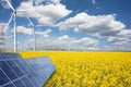 Renewable or green energy concept with wind turbines solar panels and yellow raps field on blue sky with clouds Royalty Free Stock Photo