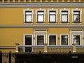 Renewed yellow wall of an old building with iron fence.