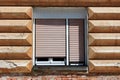 Renovated double window with white wooden frame and plastic blinds mounted on cracked striped with horizontal lines old style