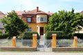 Renovated old suburban family house with new yellow facade surrounded with white picket fence and trees Royalty Free Stock Photo