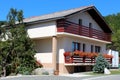 Renovated suburban family house with two long front balcones filled with red flowers next to local paved road surrounded with Royalty Free Stock Photo