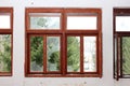 Renovated wooden window frame with broken glass and pine trees in background