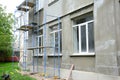 Renovating the facade of a building by applying stucco finish, plastering and finishing the exterior walls using scaffold or Royalty Free Stock Photo