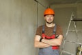 Renovation apartment. Portrait of young confident male foreman constructor repairman in safety hard hat and overalls