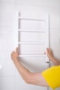 Renovation in the bathroom. A plumber installs a heated towel rail.