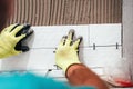 renovation close-up details - hands of worker installing ceramic tiles on bathroom walls