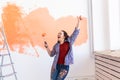 Renovation, redecoration and repair concept - Dancing funny woman painting wall in new home. Royalty Free Stock Photo