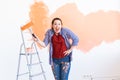 Renovation, redecoration and repair concept - Dancing funny woman painting wall in new home. Royalty Free Stock Photo