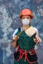 Renovation and remodelling concept. Woman in helmet and protective mask posing with hammer and spatula