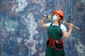 Renovation and remodelling concept. Woman in helmet and protective mask posing with hammer and spatula